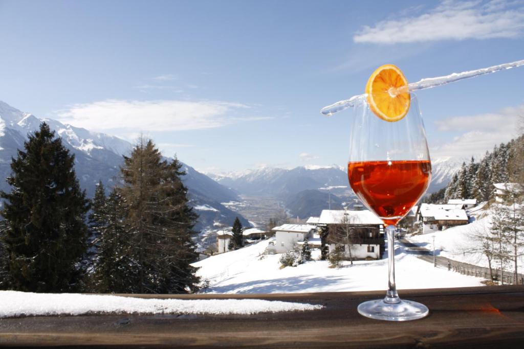 a glass of wine sitting on a table with an orange slice at Hotel Pension Tyrol in Seefeld in Tirol