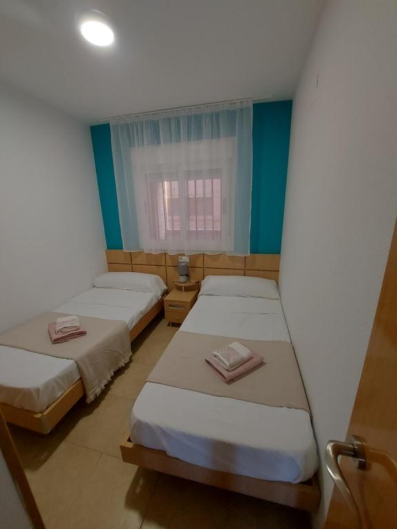 twee bedden in een kleine kamer met een raam bij Apartamento Torremar M in El Borseral
