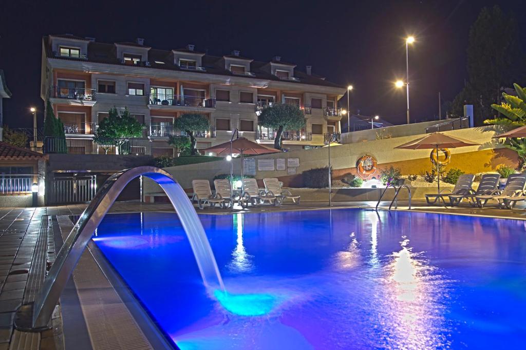 ein Schwimmbad in der Nacht mit Wasserrutsche in der Unterkunft Apartamentos Esperanza del Mar in Portonovo