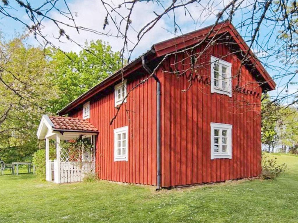 a red barn with a white door in a field at 5 person holiday home in BODAFORS-By Traum in Bodafors