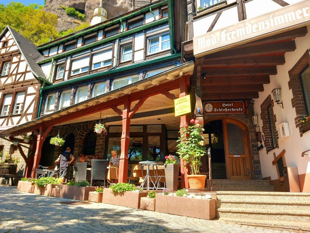 Un bâtiment avec des personnes assises à l'extérieur dans l'établissement Hotel Schloßschenke, à Idar-Oberstein