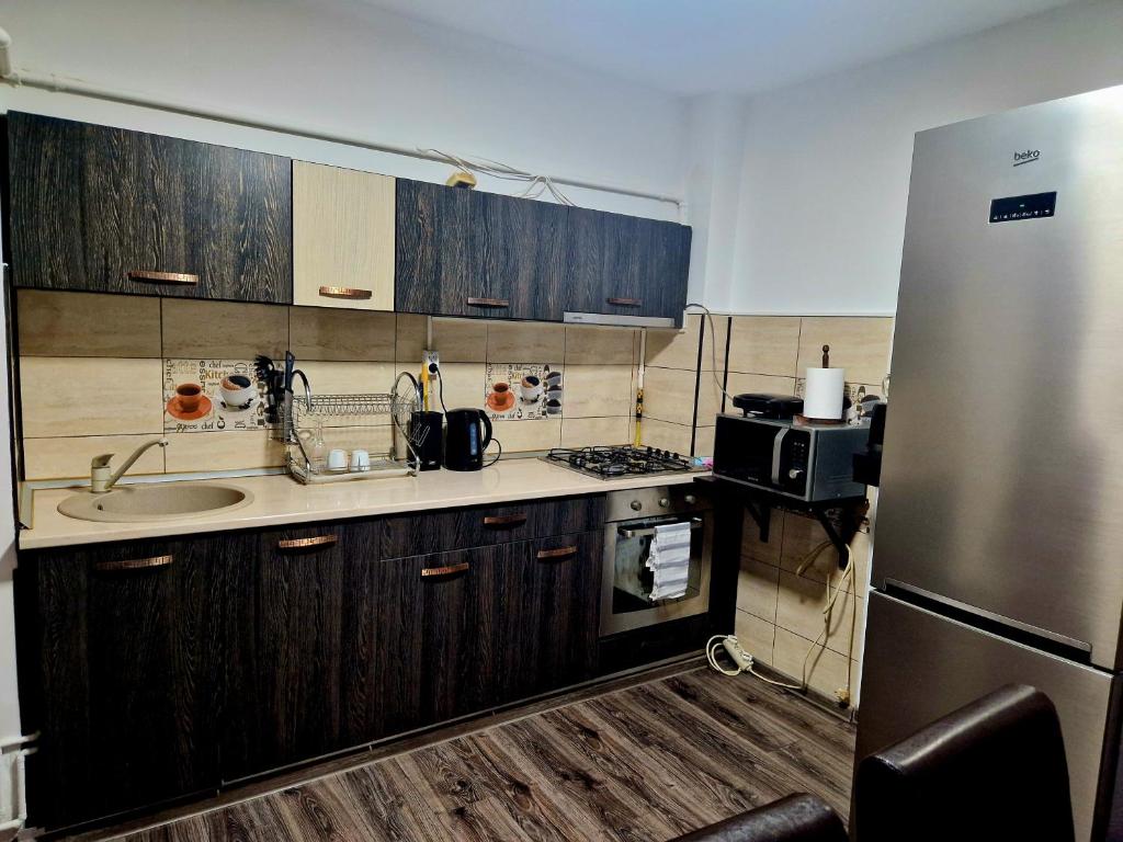 uma cozinha com armários de madeira e um frigorífico de aço inoxidável em Cozy appartment in the center em Târgovişte