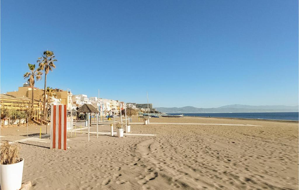 uma praia arenosa com palmeiras e o oceano em Beautiful Apartment In Torremolinos With Kitchen em Torremolinos