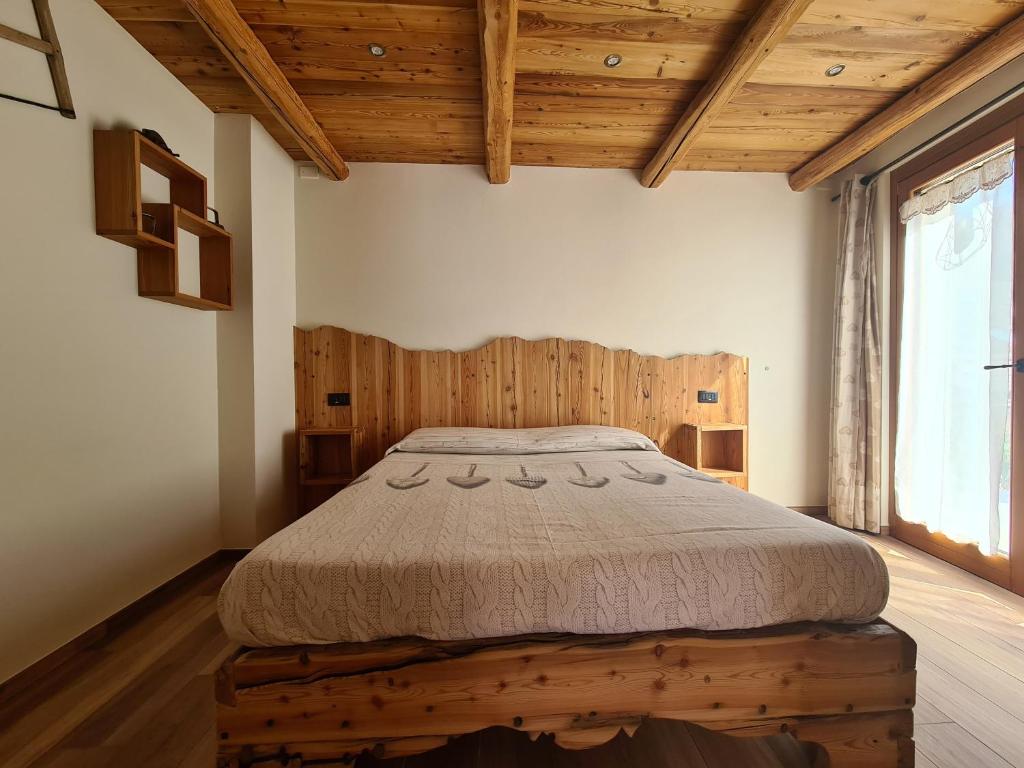 una camera con letto in una stanza con soffitti in legno di La Maison. La Roccia dello Stambecco a Bardonecchia