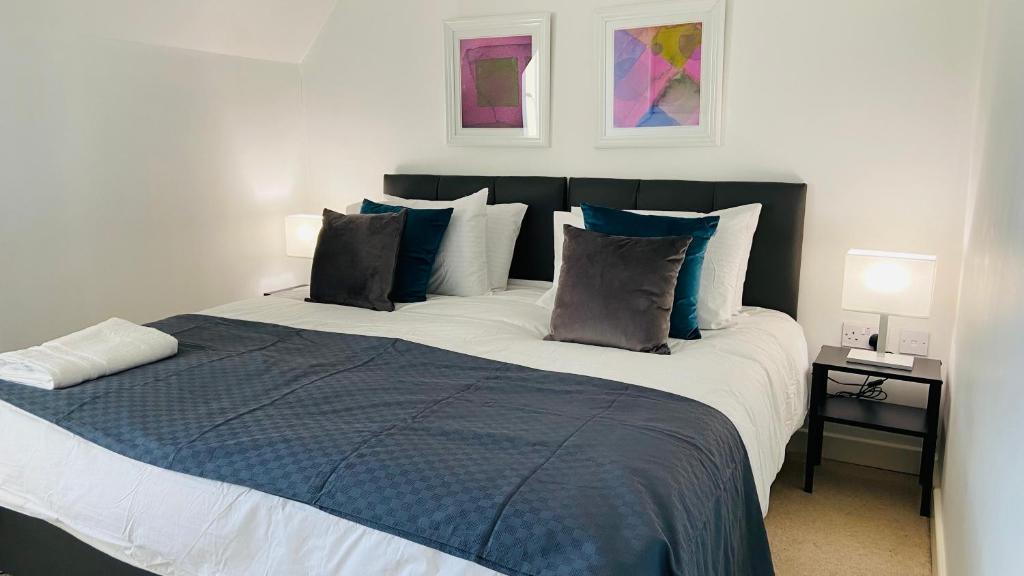 a bedroom with a large bed with blue and white pillows at Maberic Housing II in Hounslow