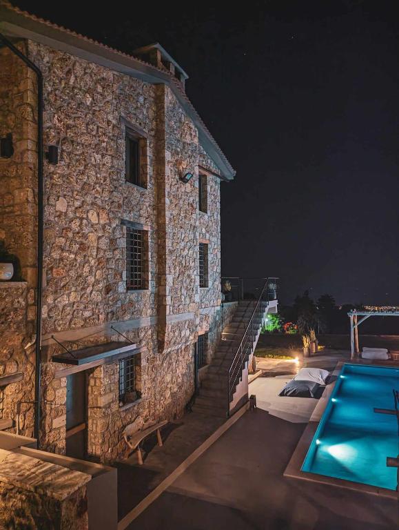 une maison en pierre avec une piscine la nuit dans l'établissement Three Dots Boutique Suites, à Soúlion