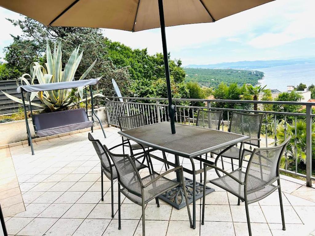 a table and chairs with an umbrella on a balcony at kutlesa 2 in Opatija