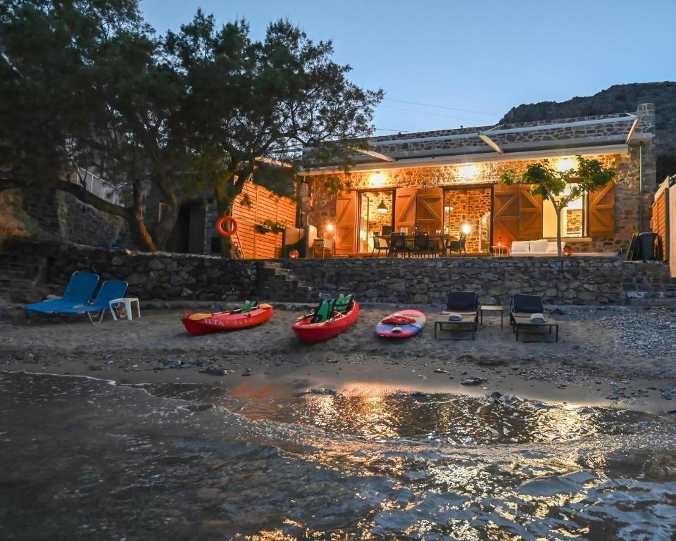 a house with kayaks on the beach in front of it at Palio Damnoni Seafront House in Damnoni