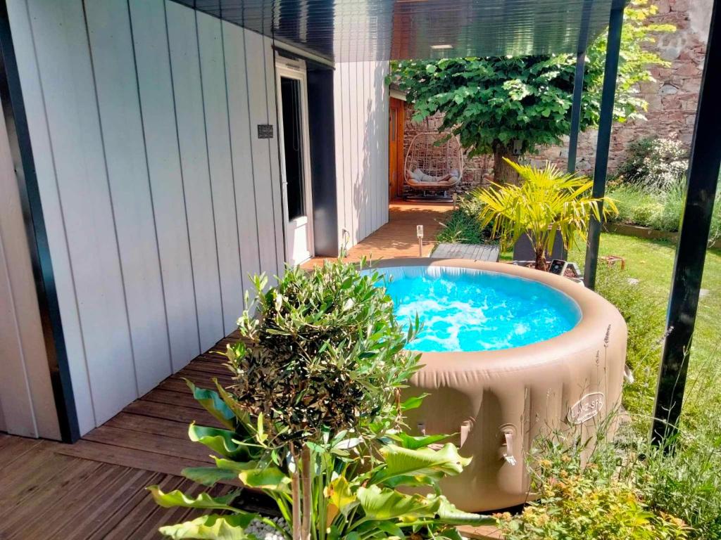 um quintal com uma banheira de hidromassagem num quintal em Séjour en amoureux avec jacuzzi et sauna em Balbigny