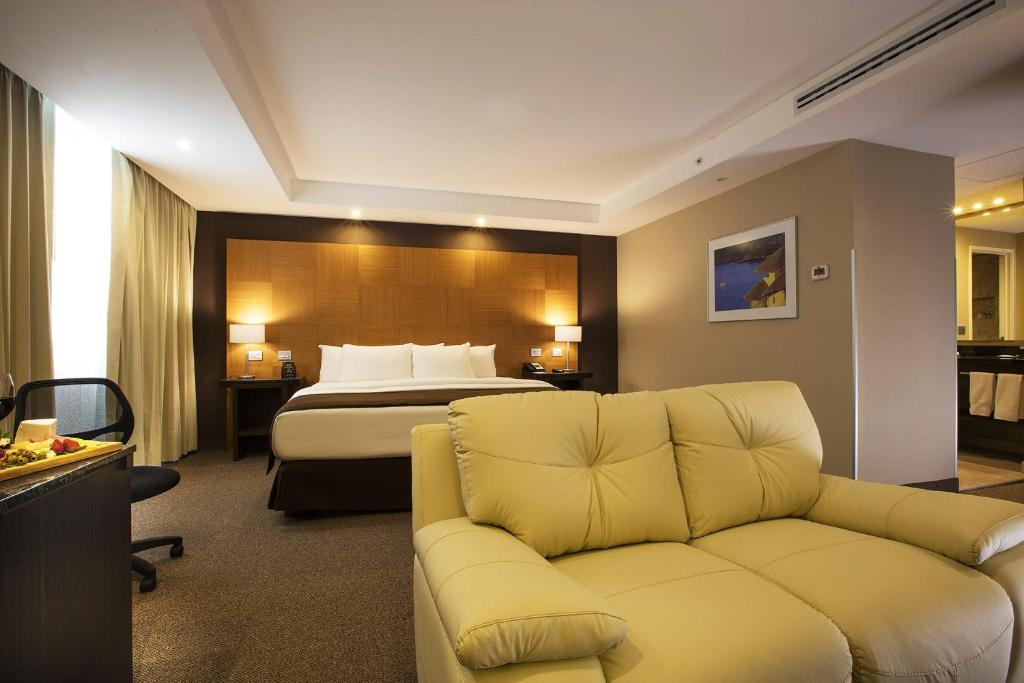 a hotel room with a bed and a couch at Krystal Urban Aeropuerto Ciudad de Mexico in Mexico City