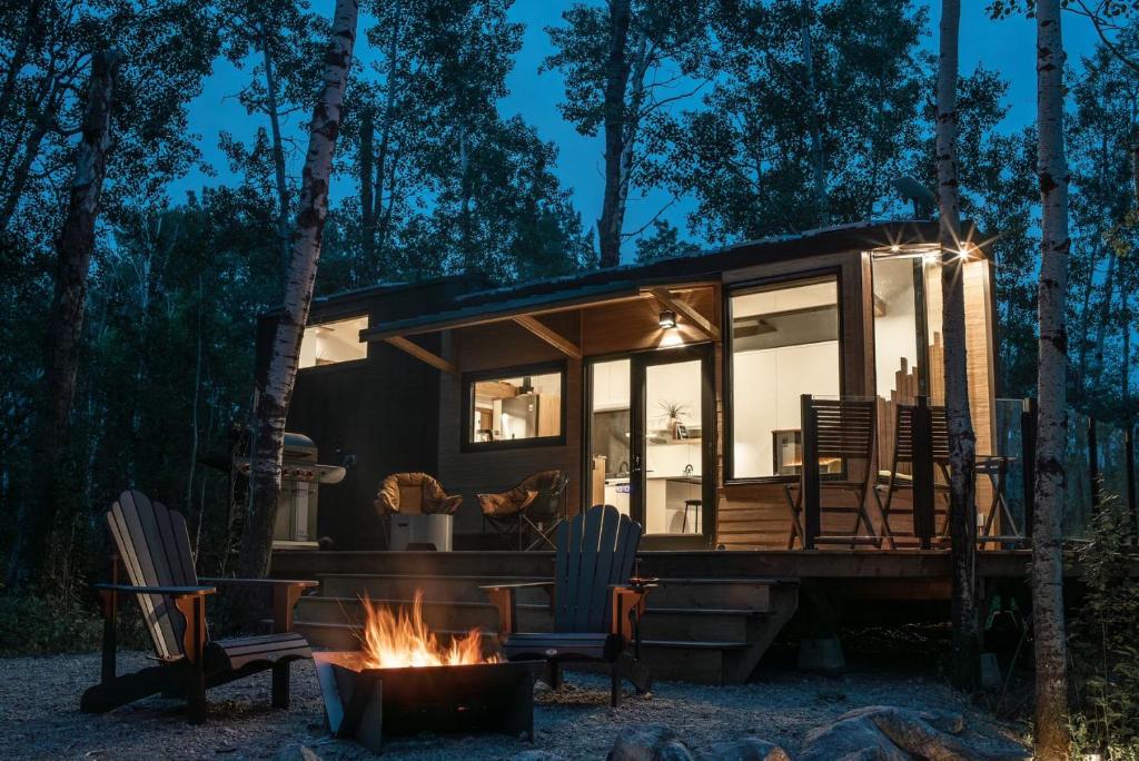 uma pequena casa na floresta com uma fogueira em Refuge Bay's Aqua Tiny Home - Luxury Off Grid Escape 