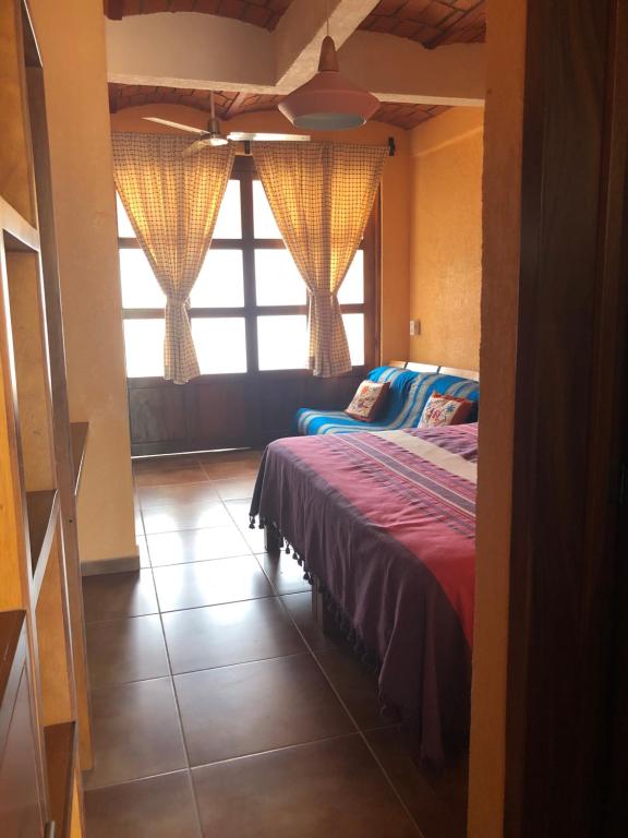 - une chambre avec un lit et une grande fenêtre dans l'établissement Mountain View Lofts Guayabitos, à Rincon de Guayabitos