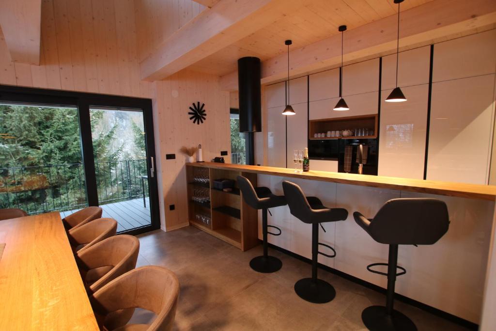 a kitchen with a bar with chairs and a table at Chata Jestřábník in Dolní Morava