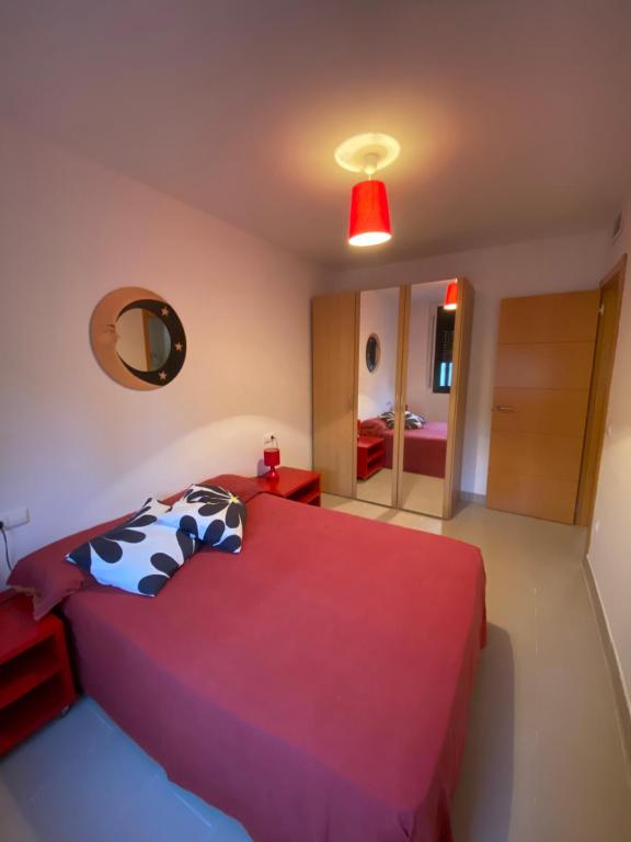 een slaapkamer met een rood bed en een spiegel bij Apartament Las Olas Cambrils in Cambrils