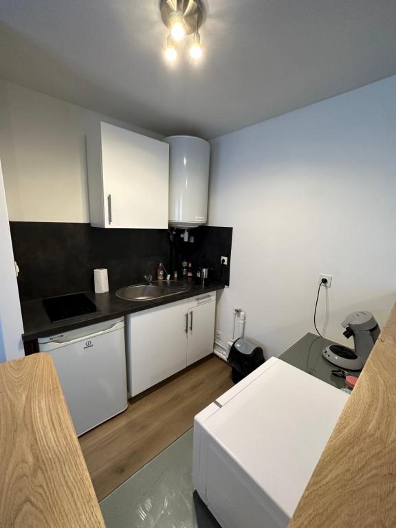 a kitchen with white cabinets and a sink at Le Jacquard in Calais