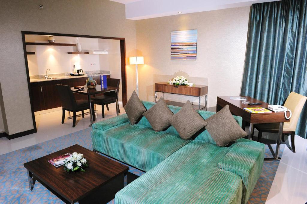 a living room with a couch and a dining room at Howard Johnson by Wyndham Abu Dhabi Downtown in Abu Dhabi