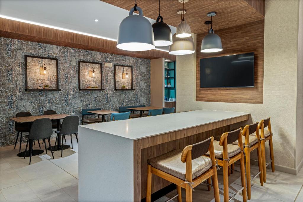 a bar in a restaurant with chairs and a flat screen tv at Fairfield by Marriott San Jose Airport Alajuela in Alajuela City
