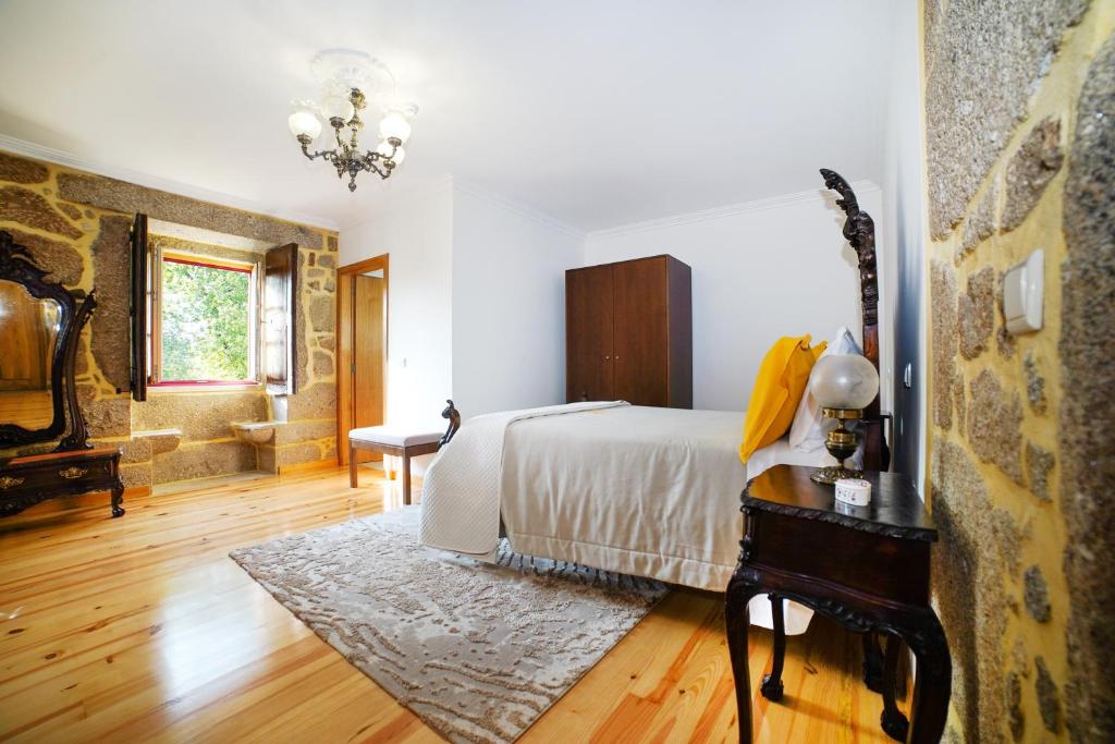 1 dormitorio con cama, mesa y lámpara de araña en Casa do Ribeiro, en Lago