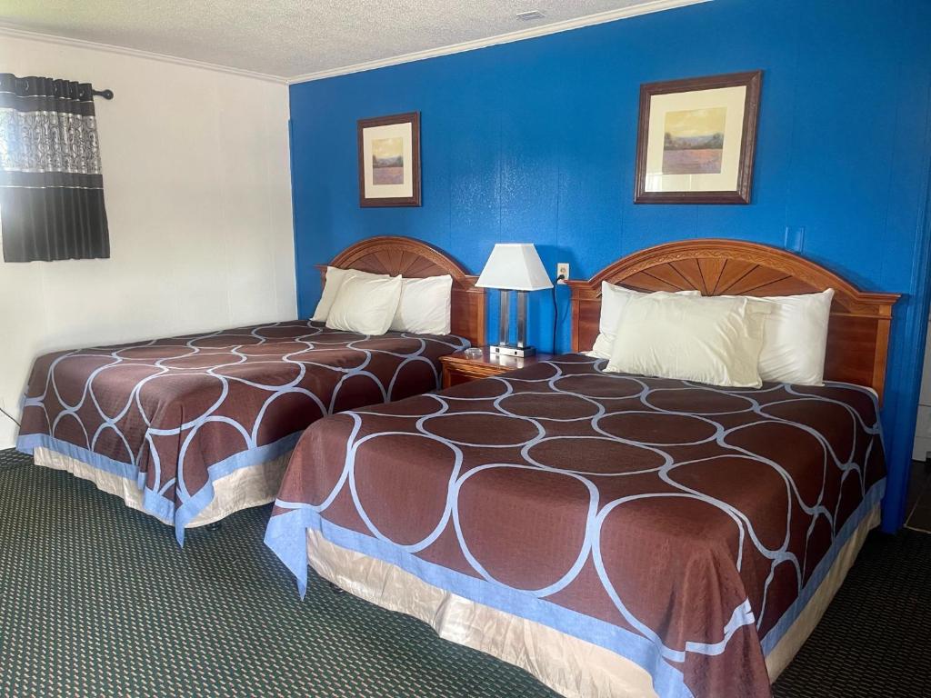 two beds in a hotel room with blue walls at Rodeway Inn in Flora
