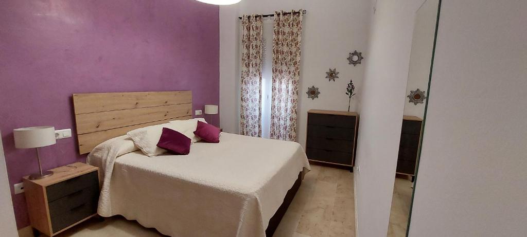 ein Schlafzimmer mit einem Bett und einer lila Wand in der Unterkunft El piso de Manuel in Sanlúcar de Barrameda