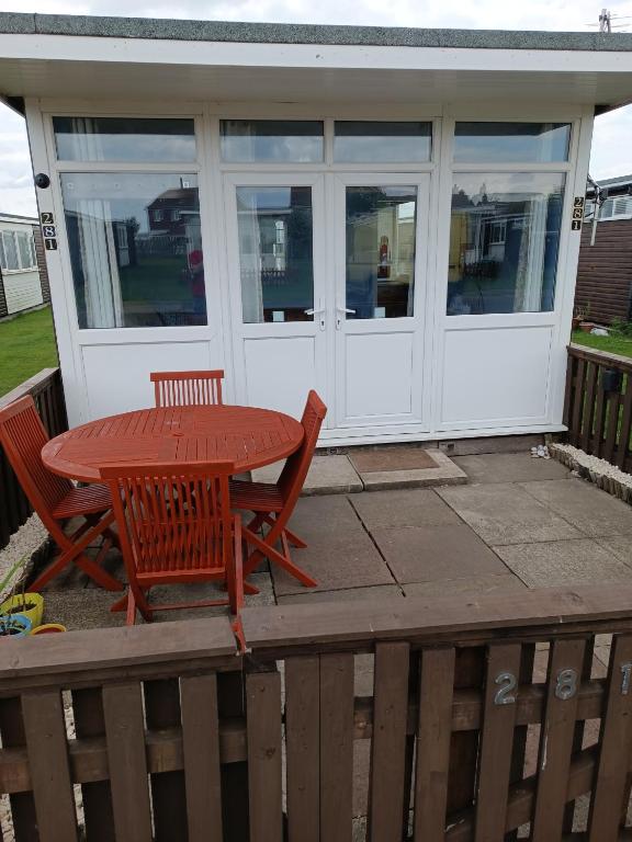 a screened in porch with a table and chairs at Chalet 281 Golden Sands Holiday Park in Withernsea