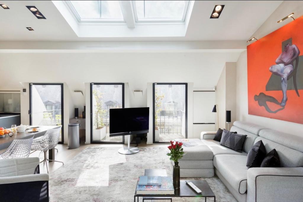 ein Wohnzimmer mit einem weißen Sofa und einem TV in der Unterkunft Prestige sur Louvre et Tuileries in Paris