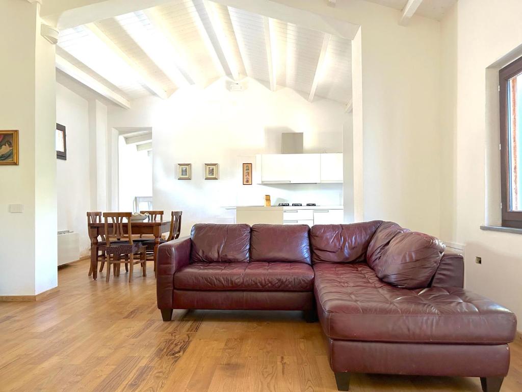 a living room with a brown leather couch and a kitchen at L'Araucaria Suite Il Ginepro in Riola Sardo