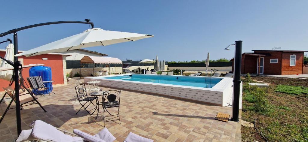 una piscina con sombrilla, mesa y sillas en UGVilla, en Arenella