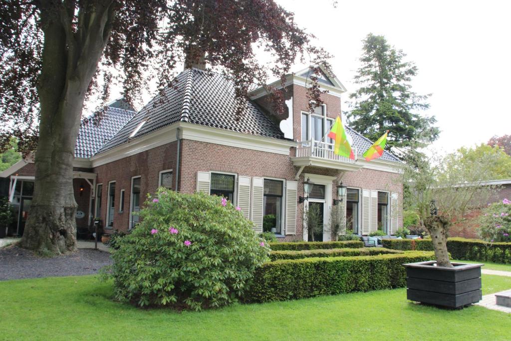 une maison avec deux drapeaux en haut dans l'établissement Hotel B&B Hoeve de Vredenhof, à Zuidlaren