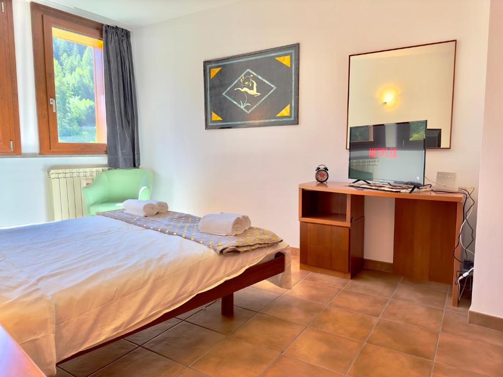 a bedroom with a bed and a desk with a television at [Paradiso di Montagna sulle piste da sci] in Bardonecchia