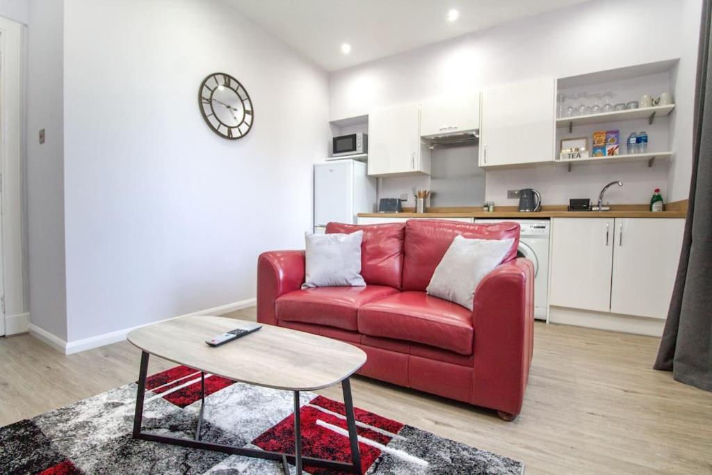 sala de estar con sofá rojo y mesa en The Ojay's - Gustina Apartment en Aberdeen