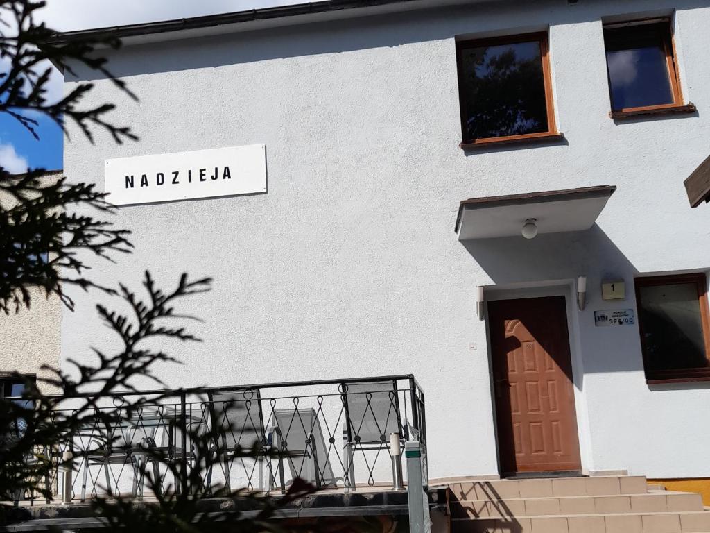 um edifício branco com uma porta e um sinal nele em Nadzieja em Jastrzebia Gora