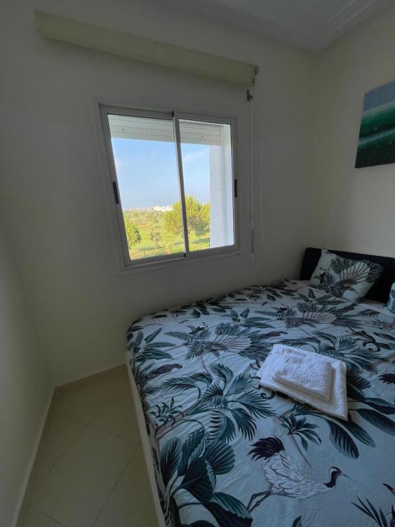 a bedroom with a bed and a window at Asilah Marina Golf, Appartement au calme in Asilah