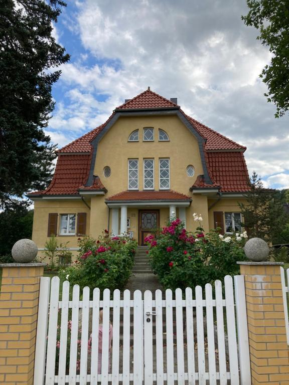 una casa amarilla con una cerca blanca delante de ella en Villa Rosengarten, en Blankenburg