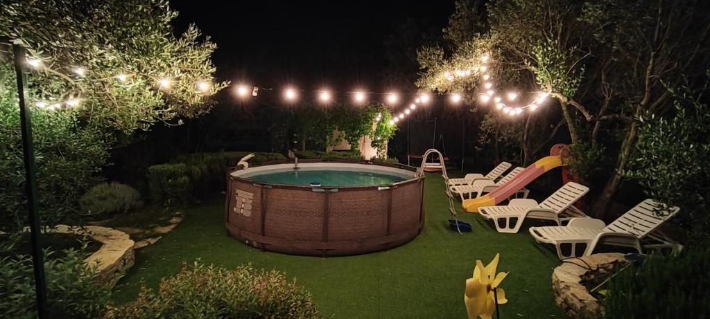 a backyard with a hot tub and chairs and lights at Apartments PHARIA in Jelsa