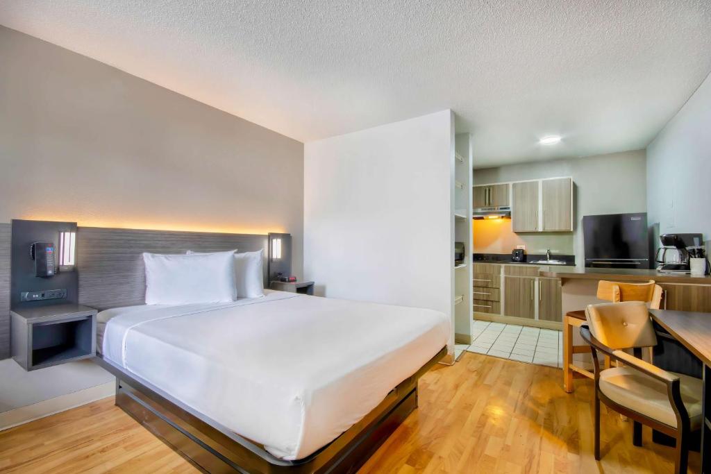 a bedroom with a large white bed and a kitchen at Studio 6-San Antonio, TX - Six Flags in San Antonio