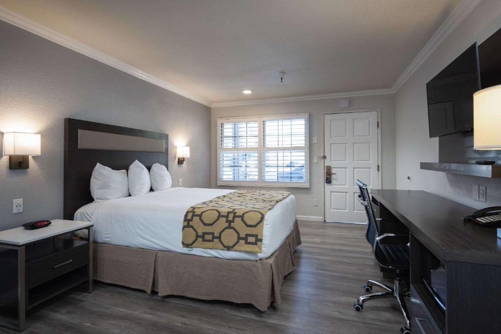 Rodeway Inn Milpitas near Great Mall في ميلبيتاس: غرفه فندقيه بسرير ومكتب ومطبخ