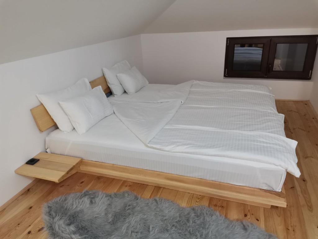 a bed with white sheets and pillows in a room at KATUN Apartmani & SPA in Divčibare