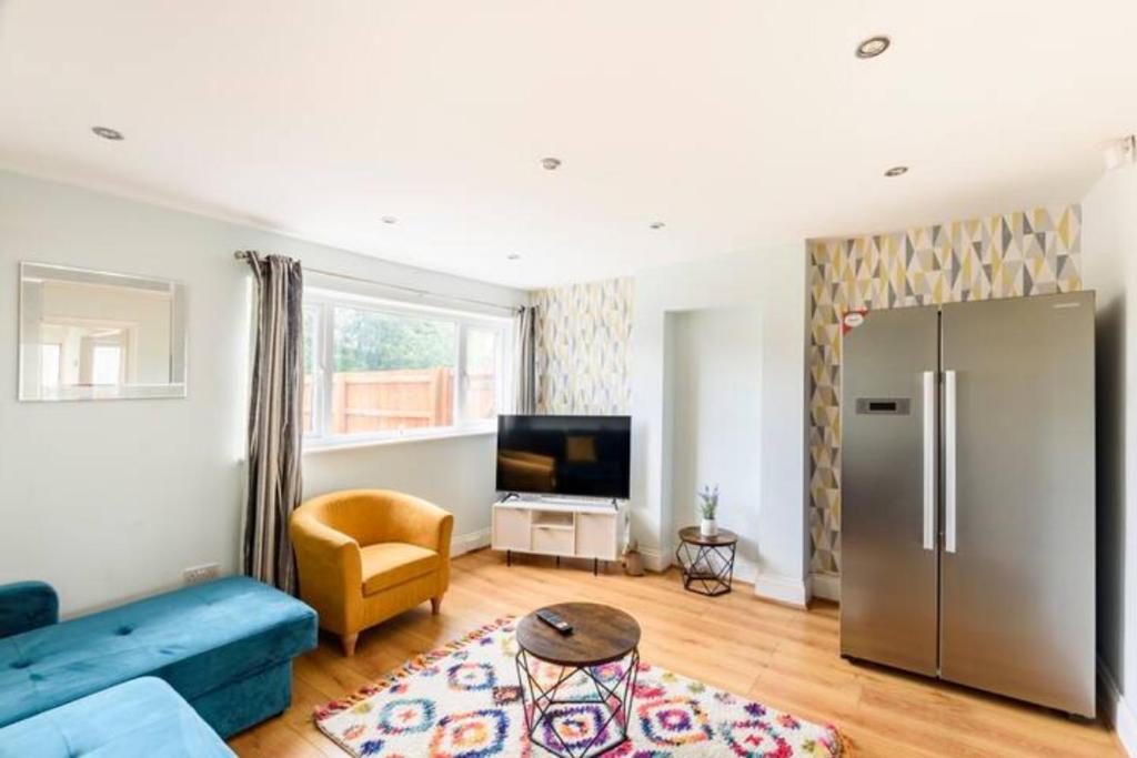 a living room with a blue couch and a refrigerator at Overbury Lodge, Birmingham with FREE Parking in Northfield