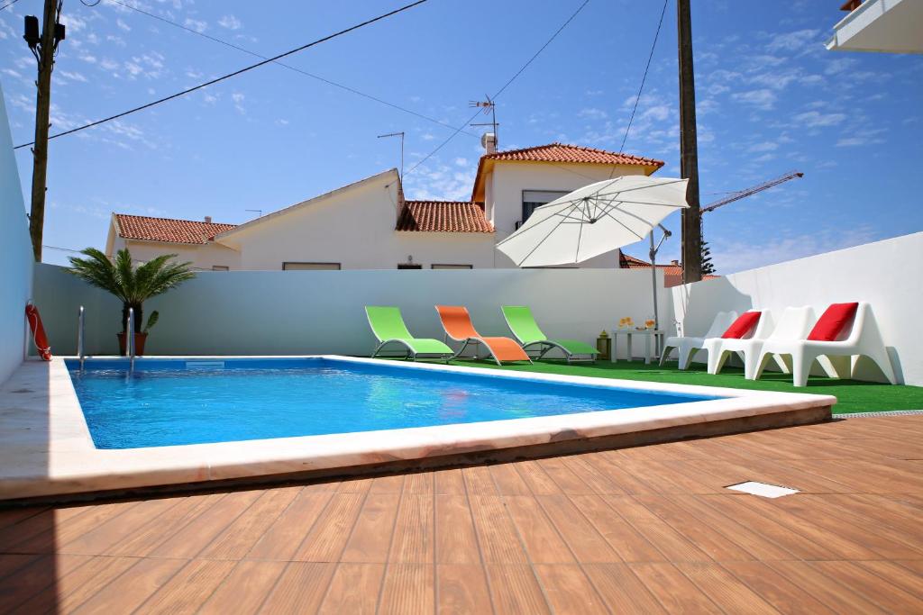 a swimming pool with chairs and an umbrella in front of a house at Zambeachouse - Hostel Paradise in Areia Branca