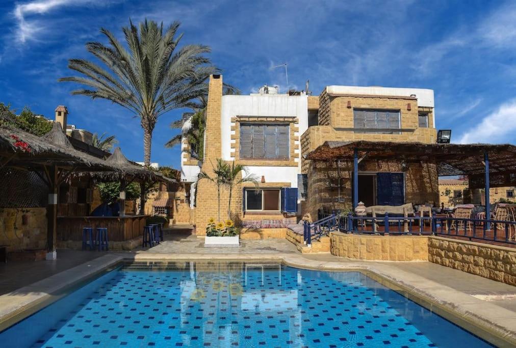 ein Haus mit einem Pool vor einem Haus in der Unterkunft Sandorini Villa for Rent in Giza