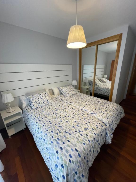 1 dormitorio con cama y espejo grande en Apartamentos Los Cubos de Llanes 3, en Llanes
