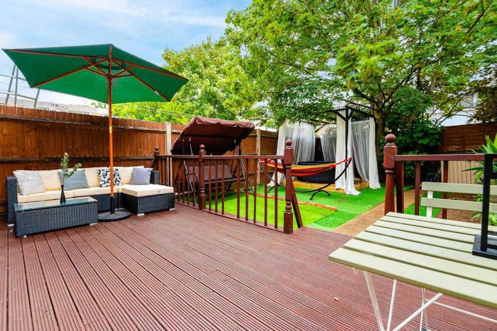eine Terrasse mit einer Hängematte und einem grünen Sonnenschirm in der Unterkunft 3Bed 2Bath with Garden sauna & Hot Tub in London