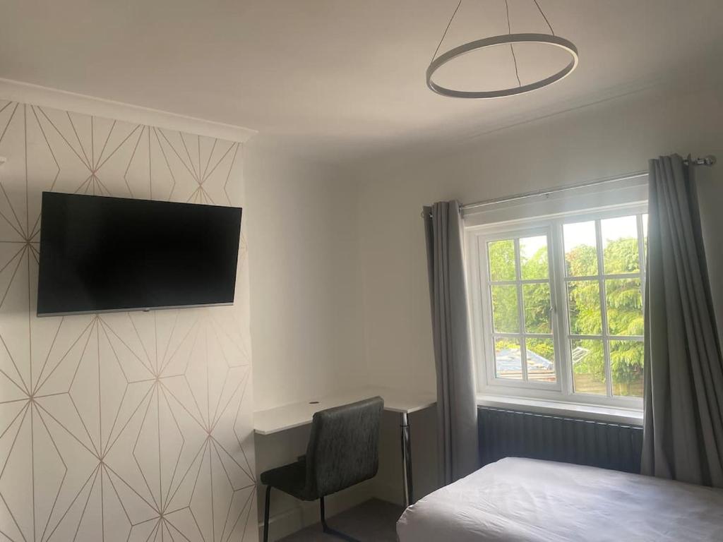 a bedroom with a bed and a desk and a television on the wall at Westminster Guest House in Oxford