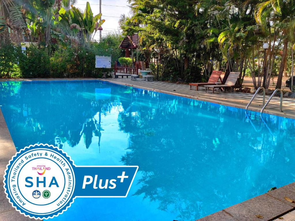een blauw zwembad in een resort met een bord waarop staat shha plus bij Thong Paeka Hotel in Prasat