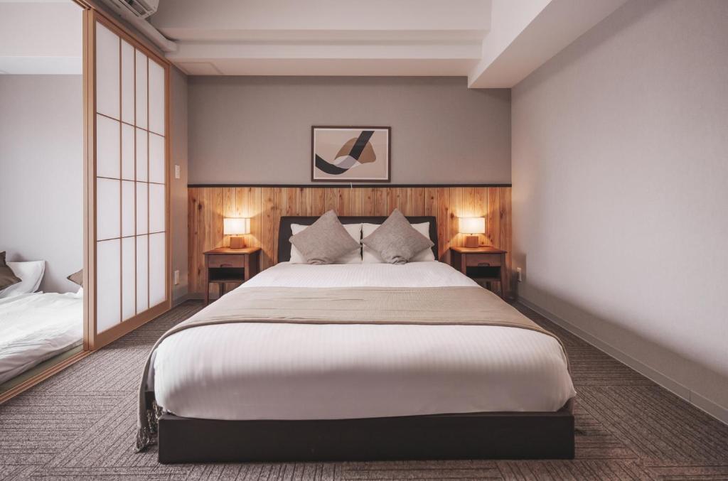 a bedroom with a large bed and two lamps on tables at 川House道頓堀 in Osaka