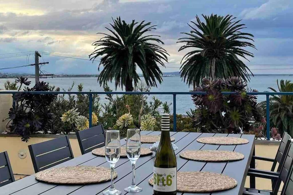 a table with glasses and a bottle of wine at Waterfront Sub-Penthouse with Beach View in Geelong
