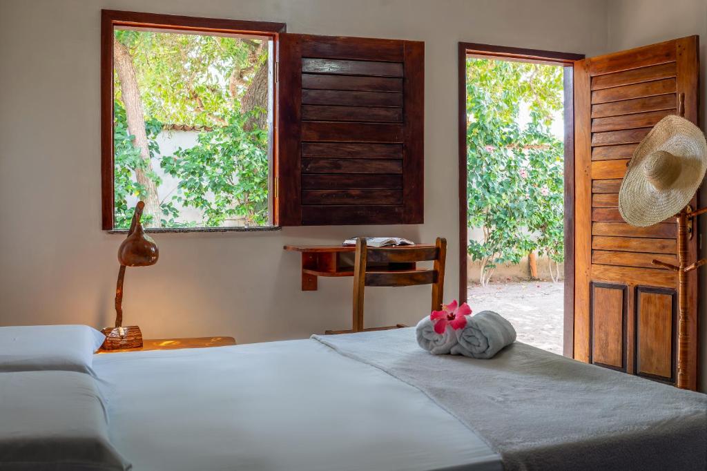 a bedroom with a bed and a table and windows at Pousada & Restaurante Flambaião in Jijoca de Jericoacoara