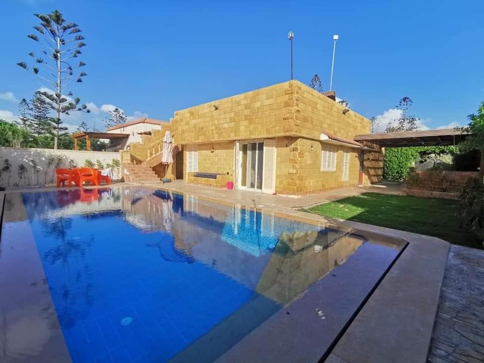 una piscina con una casa en el fondo en قرية جامعة القاهرة الكيلو 44 الساحل الشمالى 10, en Dawwār Abū Maḩrūs