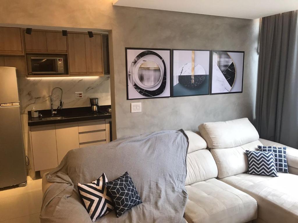 a living room with a white couch and a kitchen at Apto aconchegante vista mar , tv, wifi e ar - Praia São Vicente in São Vicente